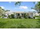 Spacious backyard with lush green grass, mature trees, and an enclosed sunroom at 1 Curacao Cir # 44, Englewood, FL 34223