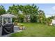 Lush backyard featuring a grill and dining set surrounded by green trees and lawn at 1 Curacao Cir # 44, Englewood, FL 34223