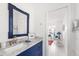 Charming bathroom boasting white counters, blue vanity, and a decorative framed mirror at 1 Curacao Cir # 44, Englewood, FL 34223
