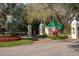 Grand entrance to a community featuring decorative columns, a guard house, and mature landscaping at 1 Curacao Cir # 44, Englewood, FL 34223