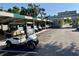 Organized row of golf carts parked beneath a covered structure with the clubhouse entrance in the background at 1 Curacao Cir # 44, Englewood, FL 34223