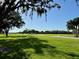 A lush golf course view features an expansive green lawn, golf carts, and mature trees on a sunny day at 1 Curacao Cir # 44, Englewood, FL 34223