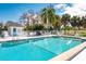 Community pool with a bathhouse and seating area surrounded by lush greenery at 1 Curacao Cir # 44, Englewood, FL 34223