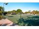 Outdoor tennis court with a well-maintained green surface and visible net surrounded by lush landscaping at 1 Curacao Cir # 44, Englewood, FL 34223