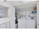 Functional laundry room with washer, dryer, storage shelves, and white cabinetry at 149 Englewood Isles Pkwy # 603, Englewood, FL 34223