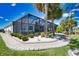 A spacious screened in lanai with pool overlooks a lush backyard with palm trees and manicured landscaping at 15176 Spanish Point Dr, Port Charlotte, FL 33981