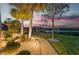 A picturesque walkway leading to a private dock at sunset is illuminated by landscape lighting and lush tropical surroundings at 15176 Spanish Point Dr, Port Charlotte, FL 33981