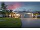Charming single-story home with a three-car garage, brick driveway, and manicured lawn under a vibrant sunset sky at 15176 Spanish Point Dr, Port Charlotte, FL 33981
