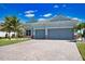 Inviting single-story home featuring a three-car garage, brick driveway, and verdant lawn under clear blue skies at 15176 Spanish Point Dr, Port Charlotte, FL 33981