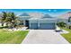Charming single-story home featuring a manicured lawn, decorative landscaping, and a three-car garage at 15176 Spanish Point Dr, Port Charlotte, FL 33981