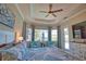 Bright bedroom with a ceiling fan, tray ceiling, large windows overlooking the pool, and coastal décor at 15176 Spanish Point Dr, Port Charlotte, FL 33981