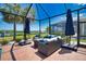 A covered patio with comfortable seating and views of the lush backyard is ideal for relaxing and enjoying the beautiful outdoors at 15176 Spanish Point Dr, Port Charlotte, FL 33981