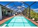 A beautiful screened-in pool with brick trim is surrounded by manicured landscaping and offers ample space for relaxation and recreation at 15176 Spanish Point Dr, Port Charlotte, FL 33981