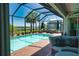 Inviting screened-in pool area featuring a pool, spa, outdoor seating, and lush landscaping near the water at 15176 Spanish Point Dr, Port Charlotte, FL 33981