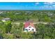 A beautiful aerial view shows a red-roofed home nestled among lush green trees in a quiet neighborhood setting at 161 Haddock Dr, Rotonda West, FL 33947