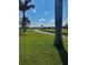 Expansive backyard view with a scenic canal, lush green grass, and towering palm trees on a clear day at 174 Broadmoor Ln, Rotonda West, FL 33947