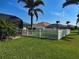 Well-manicured backyard with a lush lawn, white picket fence, and tropical palm trees on a sunny day at 174 Broadmoor Ln, Rotonda West, FL 33947