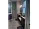 Well-lit bathroom with wood tile, dark cabinets, dual sinks, glass-block window, and built-in bench seat at 174 Broadmoor Ln, Rotonda West, FL 33947
