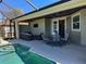 Covered lanai with seating and dining areas, overlooking the pool and landscaped backyard at 174 Broadmoor Ln, Rotonda West, FL 33947