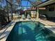 Backyard view of a screened-in pool with patio seating, landscaping, and a privacy fence at 174 Broadmoor Ln, Rotonda West, FL 33947