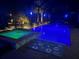A luxurious backyard pool and hot tub area is illuminated at night with palm trees in this inviting outdoor space at 174 Broadmoor Ln, Rotonda West, FL 33947
