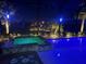 A luxurious backyard pool and hot tub area is illuminated at night with palm trees in this inviting outdoor space at 174 Broadmoor Ln, Rotonda West, FL 33947