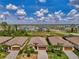 Aerial view showcases the neighborhood's well-spaced homes, mature trees, and community layout near a tranquil pond and roadway at 1836 W Isles Rd, Port Charlotte, FL 33953