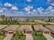 Aerial view showcases the neighborhood's well-spaced homes, mature trees, and community layout near a tranquil pond and roadway at 1836 W Isles Rd, Port Charlotte, FL 33953