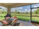 Inviting screened patio features a table and chairs, perfect for enjoying the serene backyard view at 1836 W Isles Rd, Port Charlotte, FL 33953
