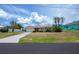 Charming single-story home featuring lush landscaping, a manicured lawn, and a long driveway at 18451 Goodman Cir, Port Charlotte, FL 33948