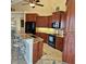 Spacious kitchen area with barstool seating, wooden cabinetry, granite counter tops and black appliances at 19 Medalist Way, Rotonda West, FL 33947