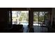 View of the patio through sliding glass doors with dining and a pool surrounded by lush landscaping at 19 Medalist Way, Rotonda West, FL 33947