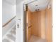 Interior view of a home elevator next to carpeted stairs with wood railing at 1900 Illinois Ave, Englewood, FL 34224