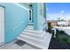 Stylish front entrance with a light blue exterior, a staircase leading to the front door and a green decorative shrub at 1900 Illinois Ave, Englewood, FL 34224