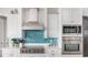 Gourmet kitchen with stainless appliances, white cabinets, and a vibrant blue backsplash for a modern touch at 1900 Illinois Ave, Englewood, FL 34224