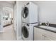 Modern laundry area with stacked washer and dryer, sink, and white cabinets at 1900 Illinois Ave, Englewood, FL 34224