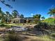 Expansive backyard showcasing the screened-in patio, tropical trees, and gravel path at 237 Rotonda E Blvd, Rotonda West, FL 33947