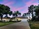 Inviting single-story home with a long driveway and mature trees at dusk at 237 Rotonda E Blvd, Rotonda West, FL 33947