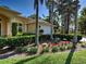 Landscaped front yard featuring red flowers, trimmed shrubs, and several palm trees under a clear blue sky at 237 Rotonda E Blvd, Rotonda West, FL 33947