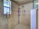 Tiled shower with installed shelving, multiple shower heads, and a window to provide natural light at 237 Rotonda E Blvd, Rotonda West, FL 33947