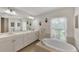 Bathroom featuring dual sinks, a bathtub, and a bright window at 29 Tournament Rd, Rotonda West, FL 33947