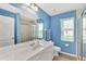 Bright bathroom with blue walls, large vanity, framed mirror, and a glass-enclosed shower at 29 Tournament Rd, Rotonda West, FL 33947