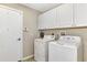 Neat laundry room with washer, dryer, and overhead cabinets for ample storage at 29 Tournament Rd, Rotonda West, FL 33947