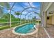Screened-in pool with a brick patio that overlooks the lawn, lake, and surrounding tropical landscaping at 29 Tournament Rd, Rotonda West, FL 33947