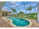 Inviting screened-in pool area with brick patio and view of the water and tropical landscaping at 29 Tournament Rd, Rotonda West, FL 33947