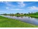 Lush green lawn sloping gently down to the canal, reflecting the blue sky and fluffy clouds at 29 Tournament Rd, Rotonda West, FL 33947