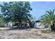 Exterior view of house with lush tree and mature palm, along with the carport on the right side of the home at 3170 Smith St, Englewood, FL 34224