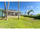 Expansive grassy backyard with partial water view and tropical foliage creating a serene outdoor space at 4093 Pelican Shores Cir, Englewood, FL 34223