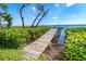 Picturesque wooden dock extending into the water surrounded by lush greenery and clear skies at 4093 Pelican Shores Cir, Englewood, FL 34223