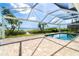 A tranquil screened pool area overlooks picturesque waterway with mature trees and inviting blue skies at 4093 Pelican Shores Cir, Englewood, FL 34223